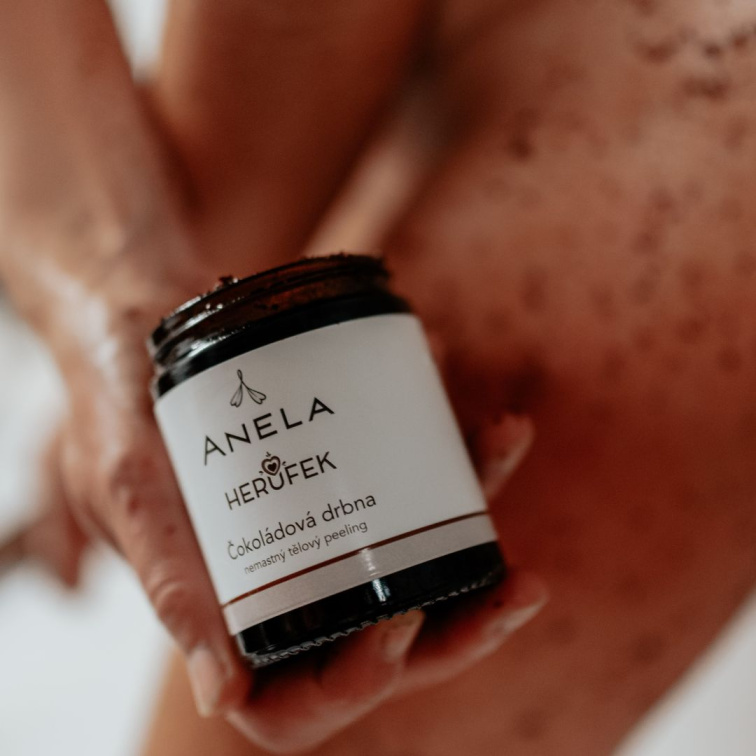 produkt - tělový peeling, držený před nohou