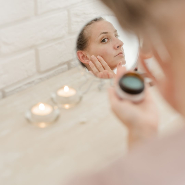 aplikace krému na obličej, žena se vidí v zrcadle
