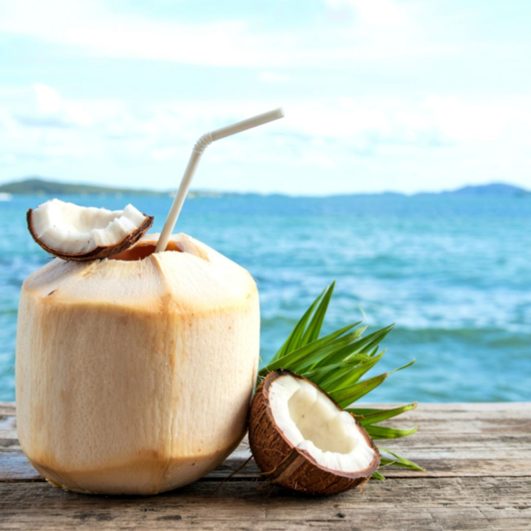 kokosový ořech v ruce ženy na pláži