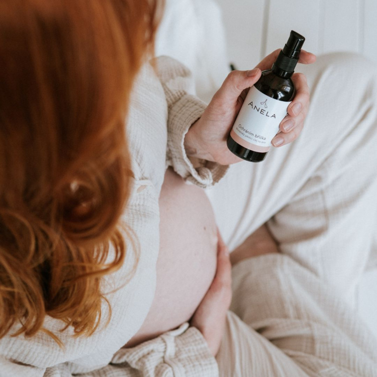 těhotná žena držící v ruce těhotenský pěsticí olej na strie Ochráním bříška