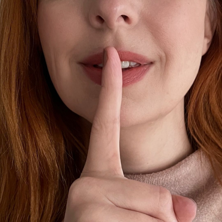 žena s prstem na ústech, skrývající tajemství