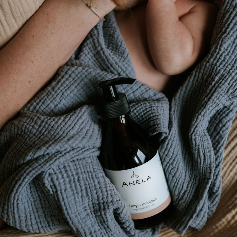 dětský mycí hydrofilní olej, položený na látkové pleně, vedle miminka