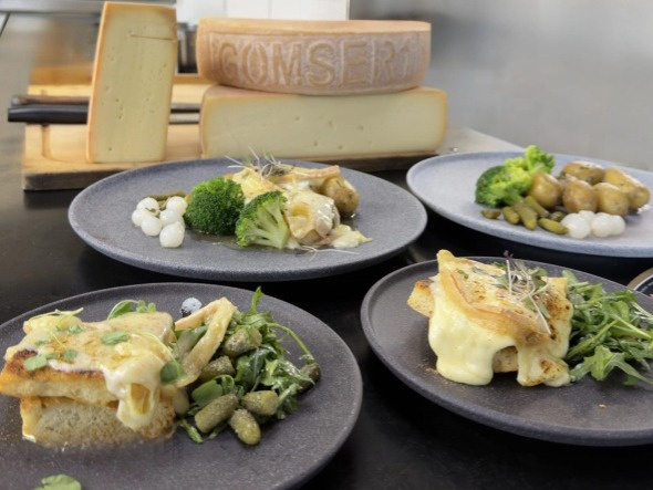 Raclette servírování – roztavený sýr a doplňky na stole