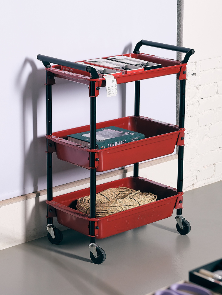Kovový dílenský vozík Toyo Steel Wagon TWR v červené barvě se třemi policemi na kolečkách, umístěný v ateliéru u zdi