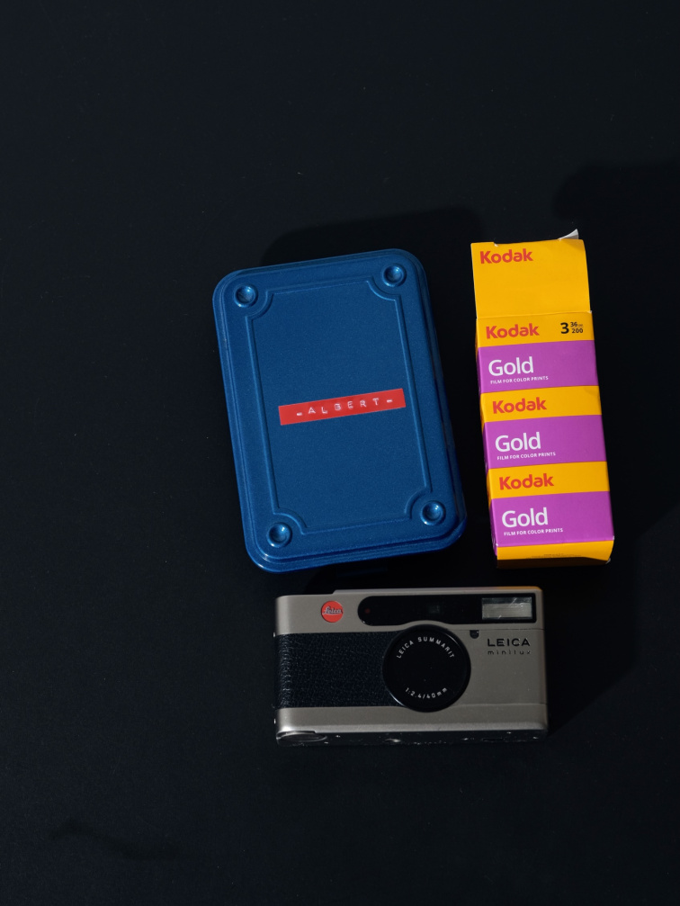 Modrý box Toyo Steel vedle analogového fotoaparátu a filmů Kodak Gold