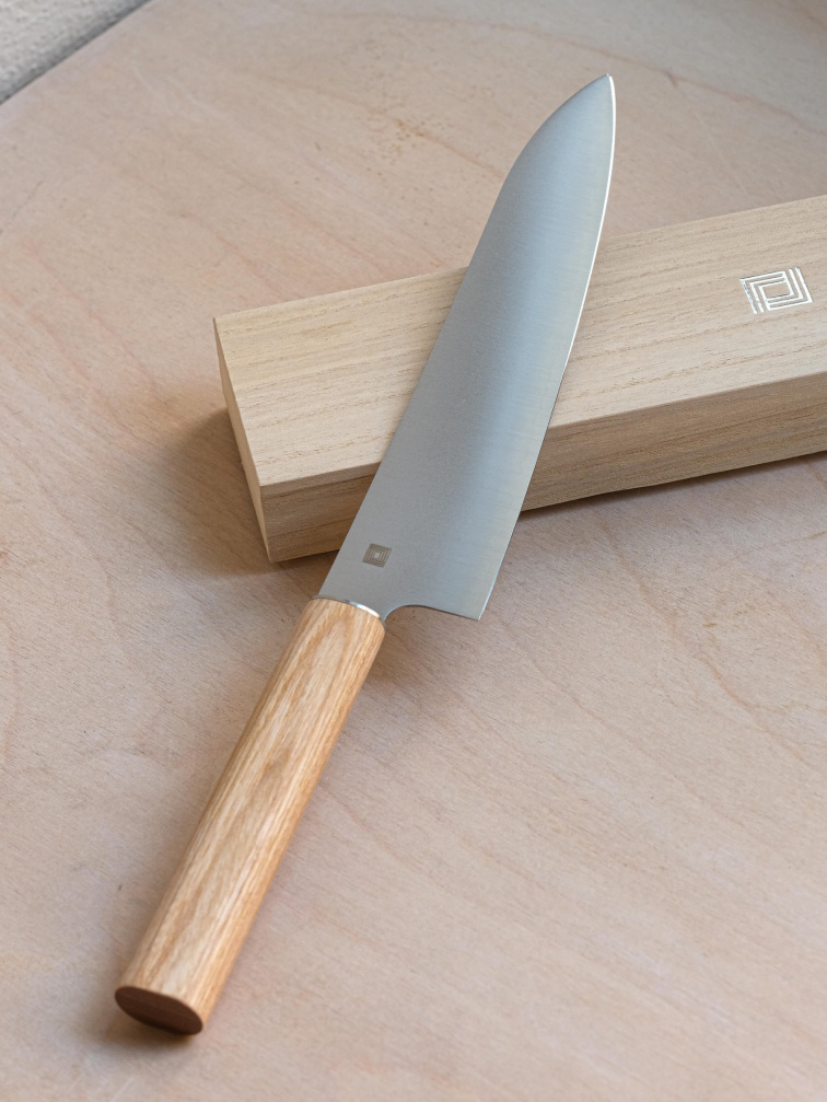 Kuchyňský nůž nasvícený přirozeným světlem na dřevěném podkladu