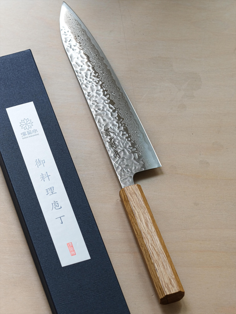 Detail japonského kuchyňského nože s dřevěnou rukojetí a kovanou čepelí