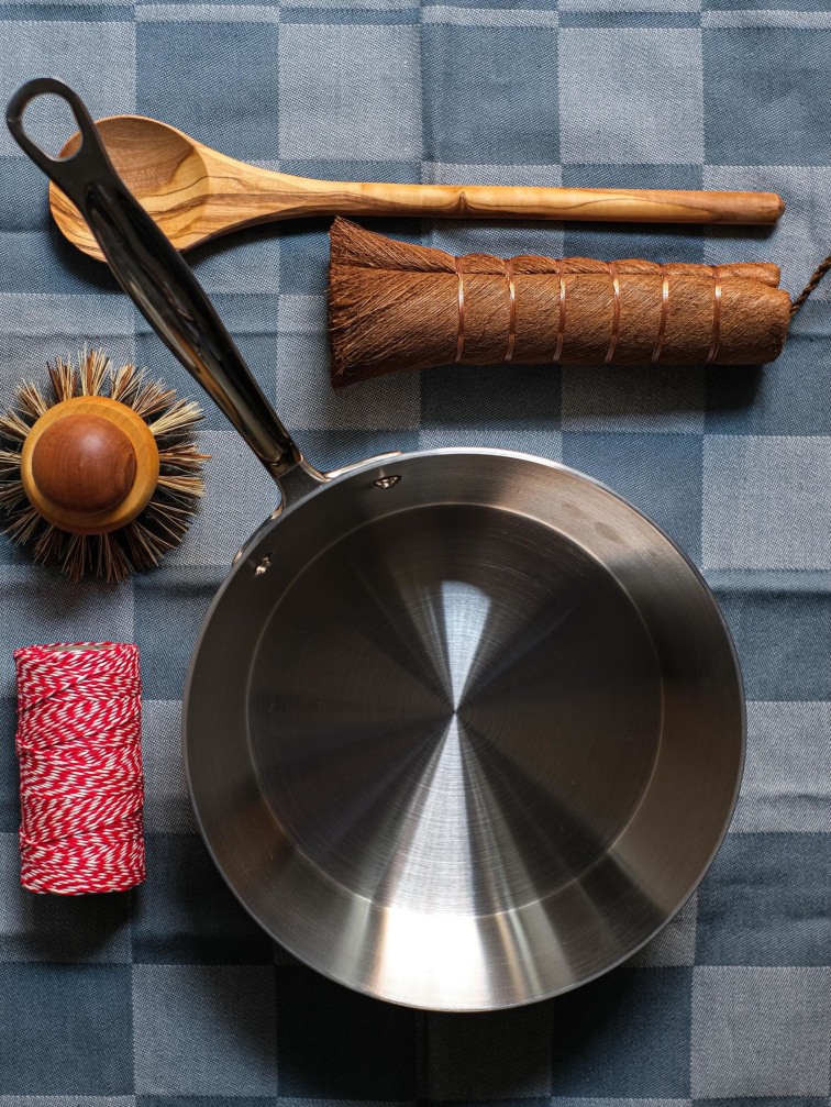 nerezová pánev s kuchyňskými nástroji a kartáčem na údržbu