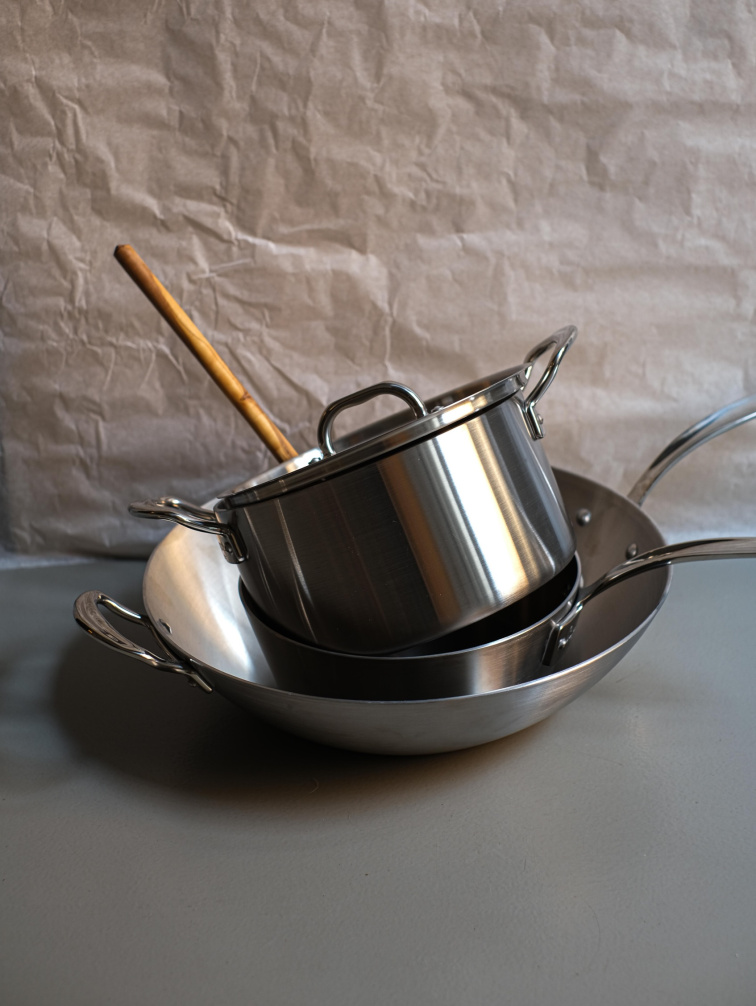 nerezové hrnce a pánev při přípravě jídla v kuchyni