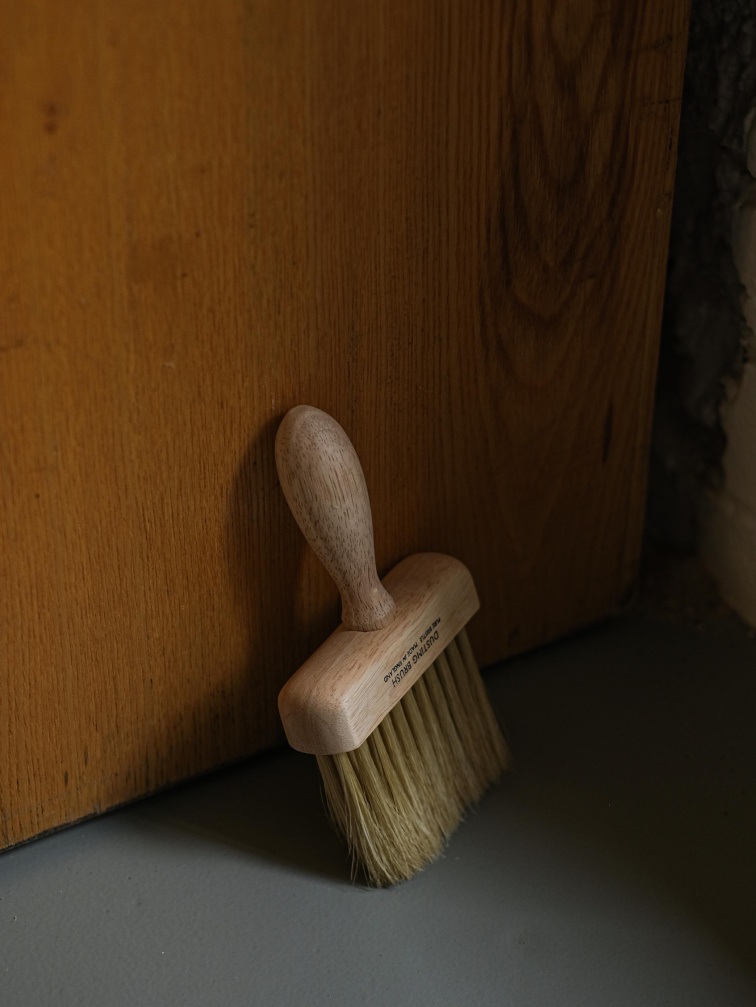 Štětec na prach R Russell bílý opřený o industriální zeď