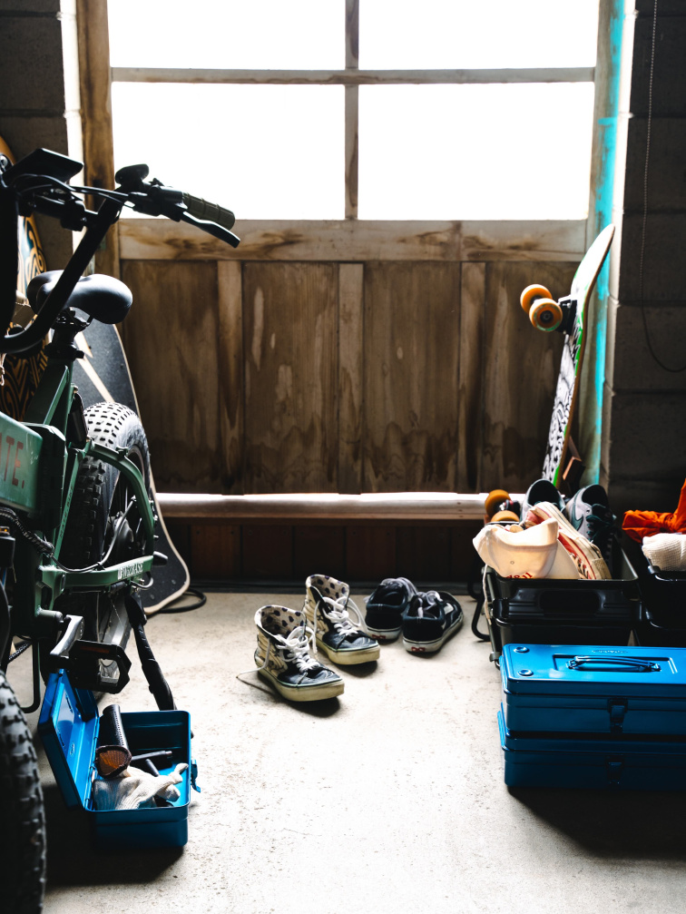 Modré úložné boxy Toyo Steel T350 a Parts Box v dílně se skateboardem a botami